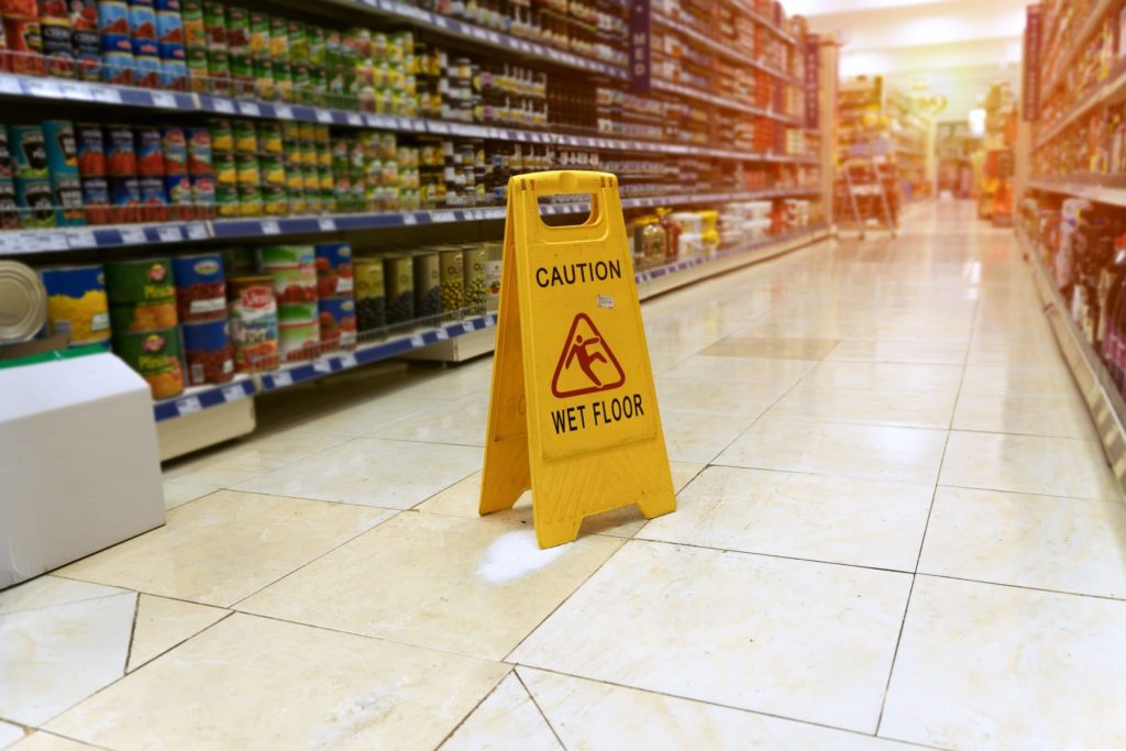 wet floor sign over slip and fall hazard in grocery store